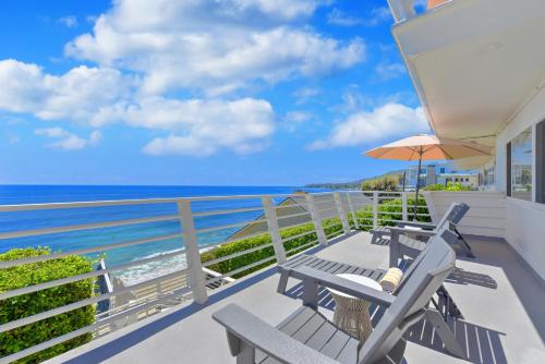 a balcony with chairs and an umbrella and the ocean at Laguna Surf Lodge by SCP Hotels in Laguna Beach