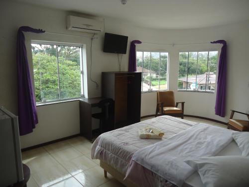 a bedroom with a bed and two windows at Iria's Hotel in Timbó