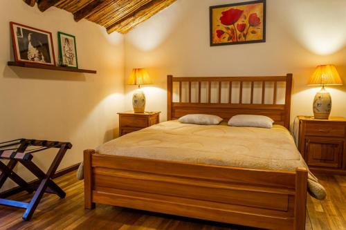 a bedroom with a bed with two lamps and two tables at Hotel Casa de las Rosas in Cuenca