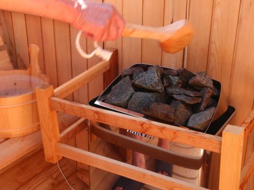 a person holding a brush next to a grill with rocks at 民泊ウトカ in Ena