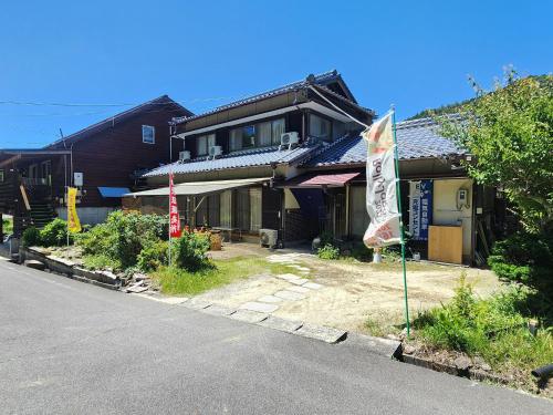 a house with a flag on the side of a street at 民泊ウトカ in Ena
