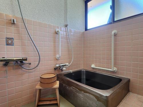 a bathroom with a tub in a pink tiled wall at 民泊ウトカ in Ena