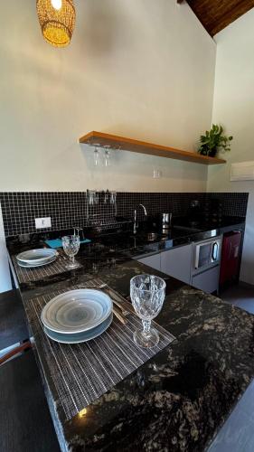 a kitchen with a counter with plates and glasses on it at Estúdio Ilhote da Prainha in Ilhabela