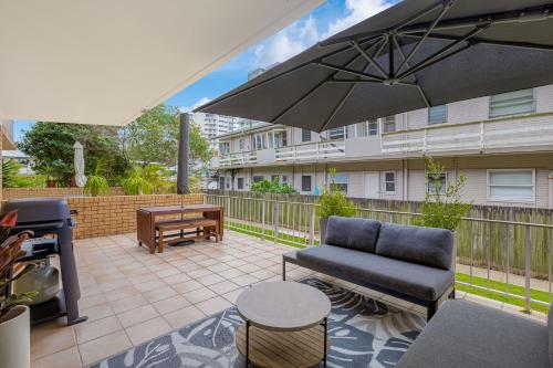a patio with a couch and an umbrella and a grill at 3 Haig Place in Gold Coast