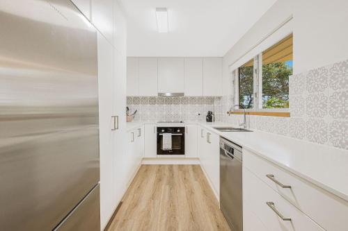 a kitchen with white cabinets and a wooden floor at 3 Haig Place in Gold Coast
