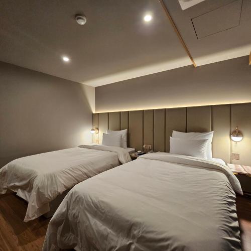 two beds in a hotel room with white sheets at Denbasta Hotel Choeup in Busan