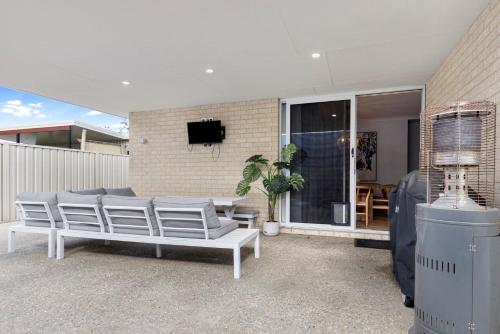 a patio with a bunch of chairs and a tv at Busselton Beachside Beauty in Busselton
