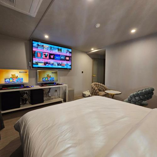 a bedroom with a bed and two flat screen televisions at Denbasta Hotel Choeup in Busan
