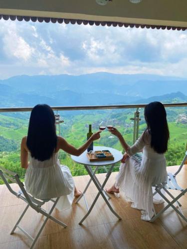 two girls sitting at a table with glasses of wine at Longji Panorama Hotel 龙脊全景楼大酒店 in Longsheng