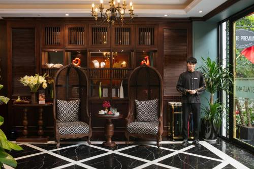 a man standing in a room with two chairs at Salute Premium Hotel & Spa in Hanoi