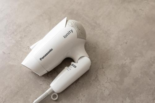 a white electric hair dryer sitting on a table at LN07 三宮中心14名まで宿泊可能! 交通至便! Sannomiya Base 2 in Kobe