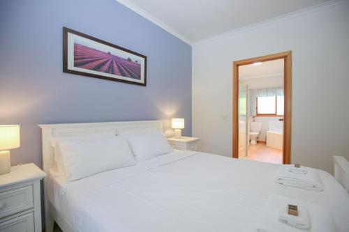 Un dormitorio con una cama blanca con un cuadro en la pared. en Bright Country Home, en Bright