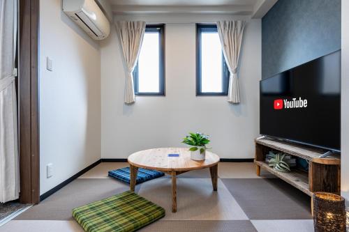 a living room with a table and a flat screen tv at AI Annex in Osaka