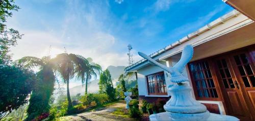 uma estátua de um pássaro sentado ao lado de uma casa em Acme Divine View em Nuwara Eliya