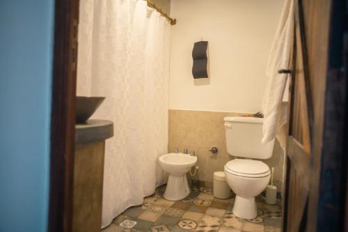 a bathroom with a toilet and a shower curtain at Loma Puskana - Hostería in Cachí