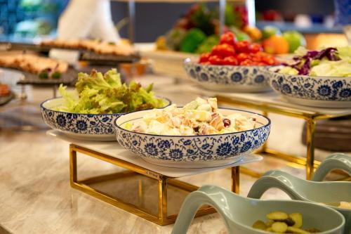 three bowls of food on a table with bowls of vegetables at Langham Honor International Hotel Canton Fair Complex Kecun Metro Station Branch - Free Shuttle Bus to Canton Fair Complex During Canton Fair Period & Free Deliver Service to Guangzhou Baiyun International Airport in Guangzhou