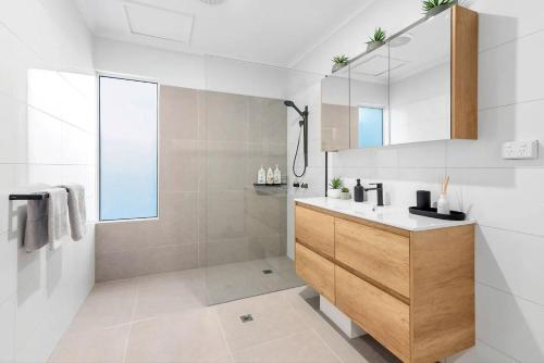 a bathroom with a sink and a mirror at Belle Escapes Sandpipers Beach House in Palm Cove
