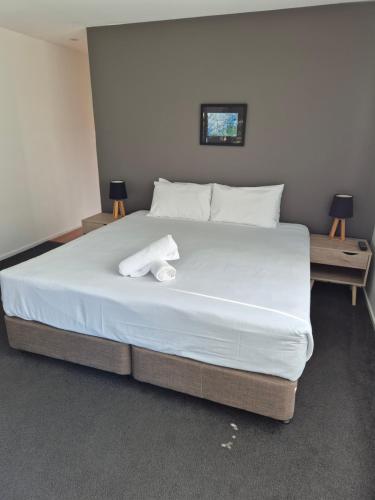a large white bed in a room with two tables at Serenity Diamond Beach in Diamond Beach
