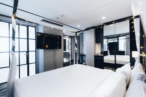 a bedroom with a large white bed and windows at Hotel NuVe Urbane in Singapore