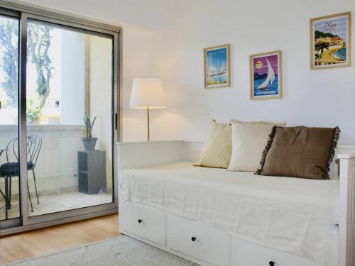 un lit blanc dans une chambre avec une fenêtre dans l'établissement Cagnes-sur-Mer: Spacieux 3 Pièces avec Piscine, Clim & Terrasses - FR-1-252A-128, à Cagnes-sur-Mer