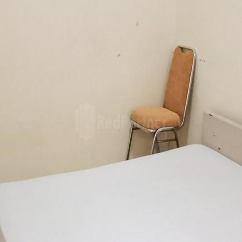 an orange chair sitting in a corner of a room at Wisma Pinggir Mitra RedDoorz in Tanjung Pinang 