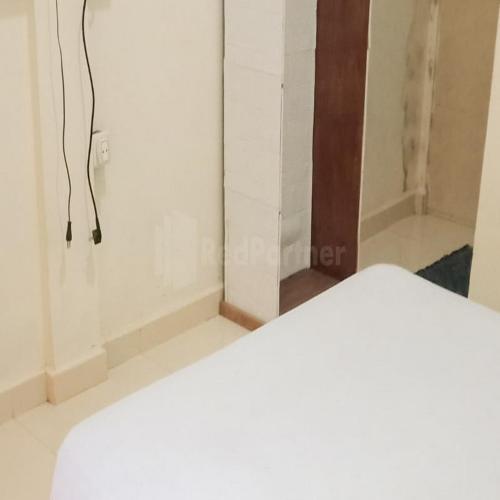 a room with a white bed and a closet at Wisma Pinggir Mitra RedDoorz in Tanjung Pinang 