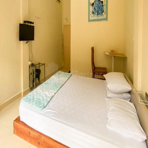 a large white bed in a room with a chair at Wisma Pinggir Mitra RedDoorz in Tanjung Pinang 