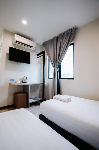 a hotel room with two beds and a television at Wangs Hotel Gurney Drive in George Town