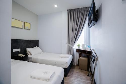 a hotel room with two beds and a television at Wangs Hotel Gurney Drive in George Town