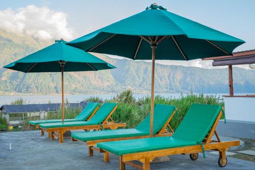 a group of chairs and umbrellas on a patio at D Sila's Tepi Danu Villas Kintamani & Natural hot spring in Kintamani