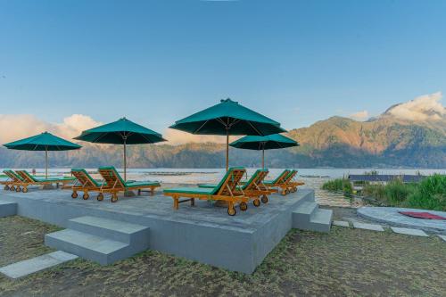 a group of lounge chairs and umbrellas on a beach at D Sila's Tepi Danu Villas Kintamani & Natural hot spring in Kintamani