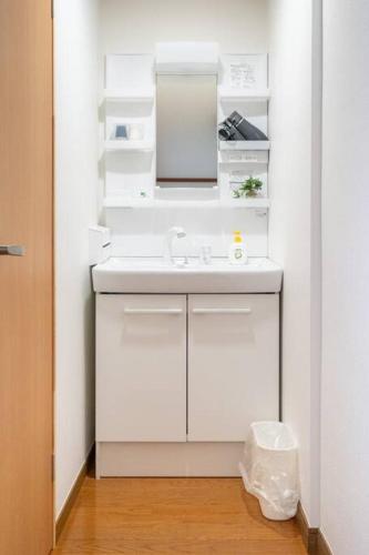 a white bathroom with a sink and a mirror at Vacation Home 和BISABI in Matsumoto