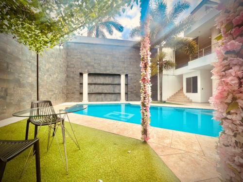 a swimming pool with a table and a palm tree at Casa Vacacional Jpol in Cali