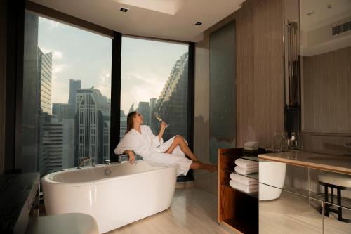 a woman sitting in a bath tub in a bathroom at Hyatt Regency Bangkok Sukhumvit in Bangkok