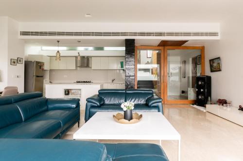 a living room with blue couches and a table at Casa De Fiesta at Vasco Da Gama by StayVista in Dabolim