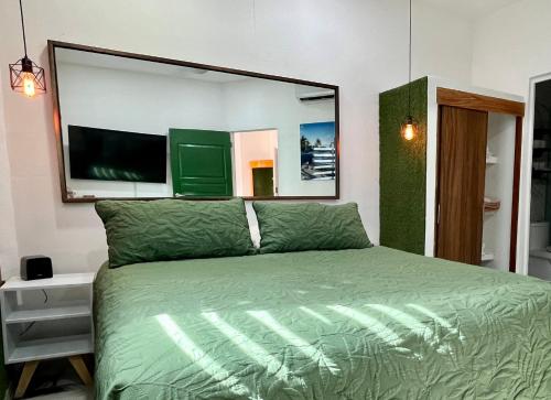 a bedroom with a green bed with a large mirror at La Puerta Blanca Penthouse #8 in Puerto Vallarta