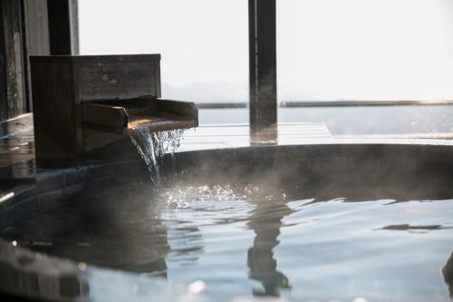 a bath tub filled with water with a fountain at Tennomaru in Gamagori