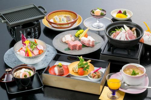 a table with plates of food on a grill at Tennomaru in Gamagori