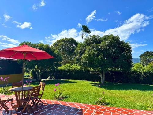 a patio with a table and a red umbrella at El Ensueño Ecohostal & Glamping in Mocoa