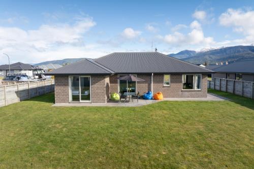 a small brick house with a grass yard at Cozy Haven - Te Anau Holiday Home in Te Anau