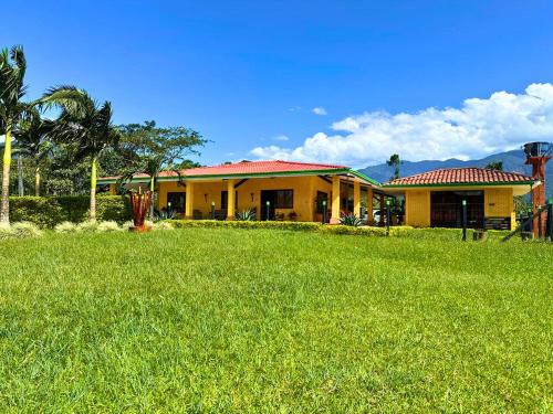 a yellow house with a green lawn in front of it at El Ensueño Ecohostal & Glamping in Mocoa