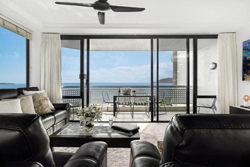 a living room with a couch and a ceiling fan at Belle Escapes 101 Rydges Plaza Esplanade with Panoramic Ocean Views in Cairns
