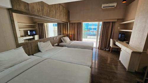 a hotel room with two beds and a desk at Student Park Hotel in Yogyakarta