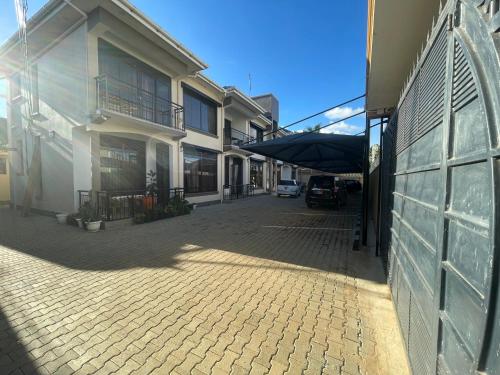 a cobblestone street next to a white building at Cozy Home in Entebbe in Entebbe