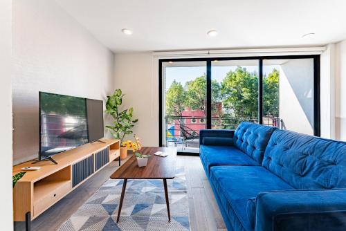 a living room with a blue couch and a flat screen tv at Roma Sur Apartments by VH in Mexico City