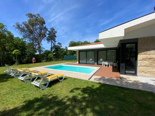 a pool with lounge chairs and a house at Casa tapada da cheda 1 in Fafe