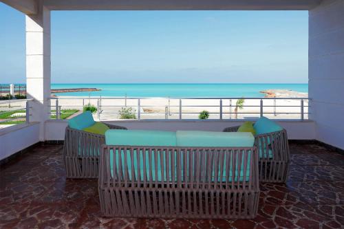 a balcony with a table and chairs on the beach at Gewan Palace New Alamein in El Alamein