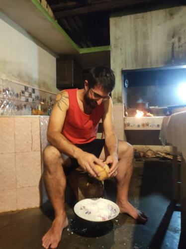 a man sitting on a rock in a kitchen preparing food at Jaana Guest in Sigiriya
