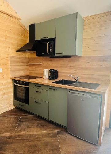 une cuisine avec un évier et un micro-ondes dans l'établissement Le chalet aux portes du pays d Auge, à Saint-Samson