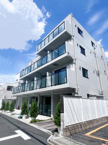 a white building with glass windows on a street at Real Okubo Apartment Hotel in Tokyo